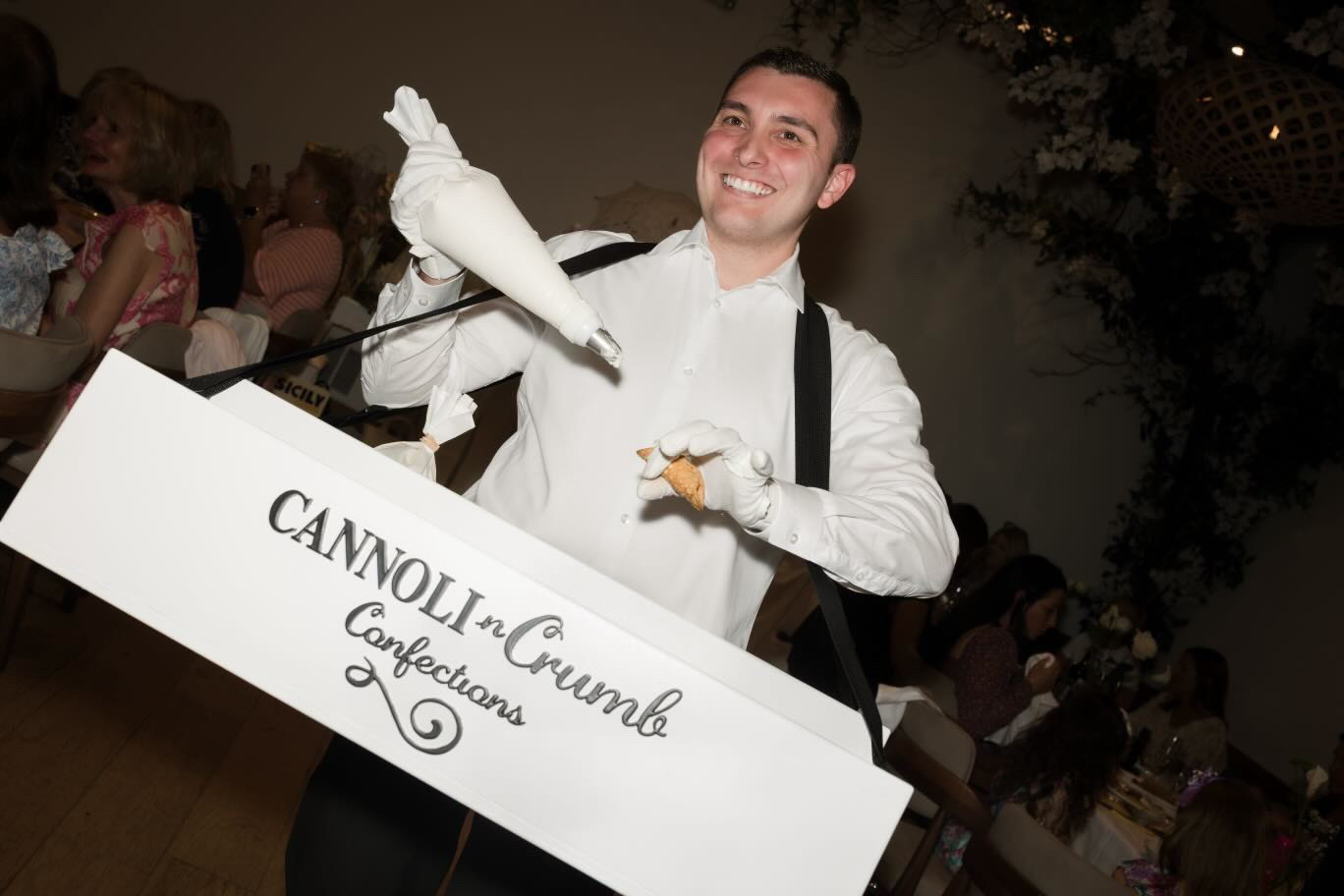 Hand-piping cannoli from the branded strolling tray at an indoor event
